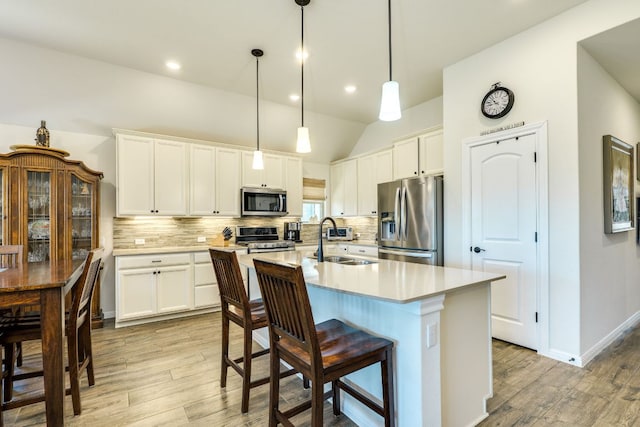 22208 Coyote Cave Trl, Spicewood, TX 78669 - kitchen with stainless steel appliances, a sink, light wood-style floors, light countertops, and decorative backsplash