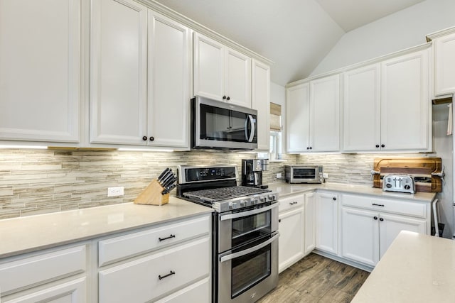 22208 Coyote Cave Trl, Spicewood, TX 78669 - kitchen featuring appliances with stainless steel finishes, vaulted ceiling, light countertops, backsplash, and white cabinetry