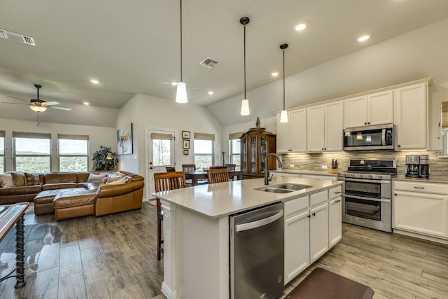 22208 Coyote Cave Trl, Spicewood, TX 78669 - kitchen with stainless steel appliances, a sink, open floor plan, decorative backsplash, and vaulted ceiling