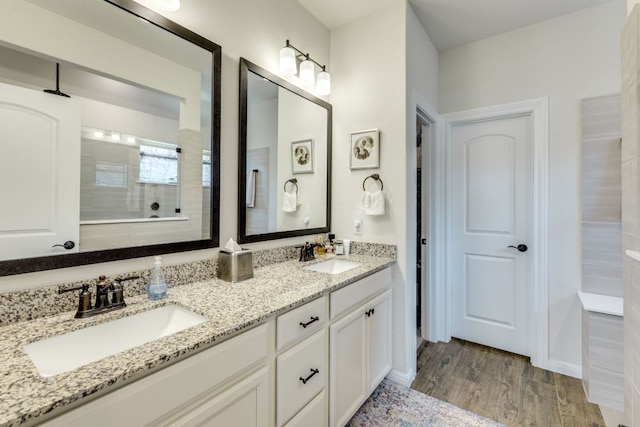 22208 Coyote Cave Trl, Spicewood, TX 78669 - bathroom featuring double vanity, wood finished floors, and tiled shower