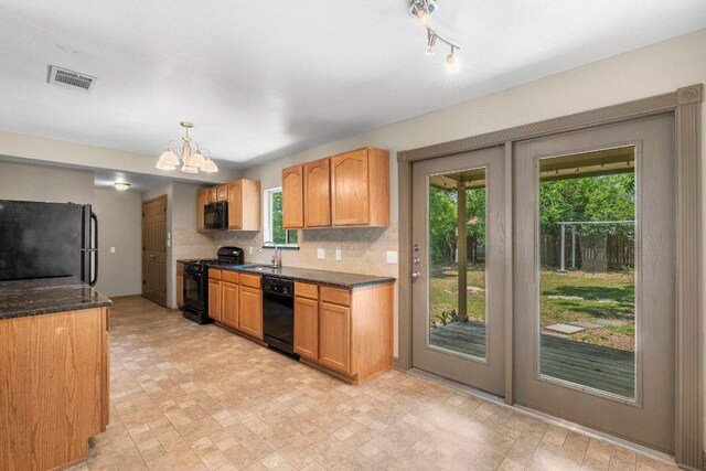 1203 Haynes St, San Marcos, TX 78666 - kitchen with black appliances, a chandelier, decorative backsplash, hanging light fixtures, and dark stone counters