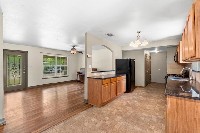 1203 Haynes St, San Marcos, TX 78666 - kitchen with black appliances, a chandelier, brown cabinets, a ceiling fan, and dark stone counters