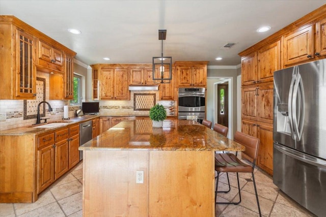 2901 Olympia Dr, Temple, TX 76502 - kitchen featuring appliances with stainless steel finishes, crown molding, a sink, stone countertops, and a breakfast bar area