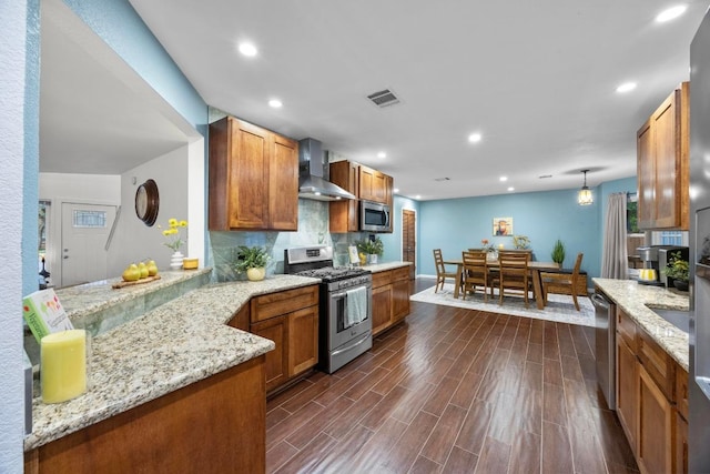 1303 Shady Grove Path, Cedar Park, TX 78613 - kitchen with stainless steel appliances, wall chimney range hood, dark wood-type flooring, brown cabinetry, and light stone counters
