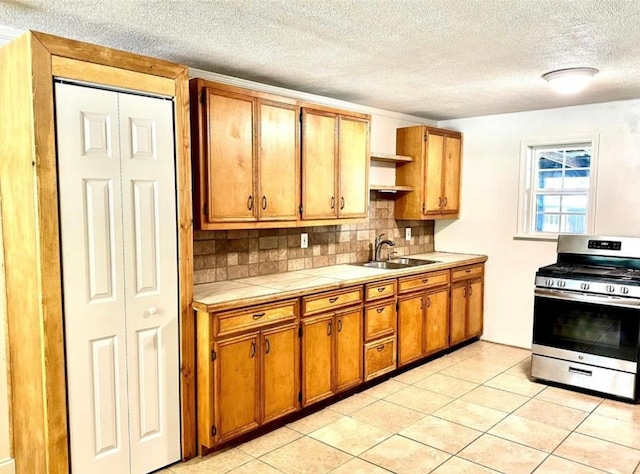 101 Byrne St, Smithville, TX 78957 - kitchen featuring stainless steel range with gas cooktop, a sink, tasteful backsplash, open shelves, and brown cabinetry