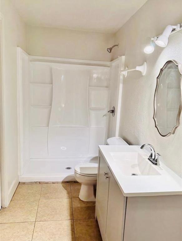 101 Byrne St, Smithville, TX 78957 - bathroom featuring a shower stall, toilet, tile patterned flooring, and vanity