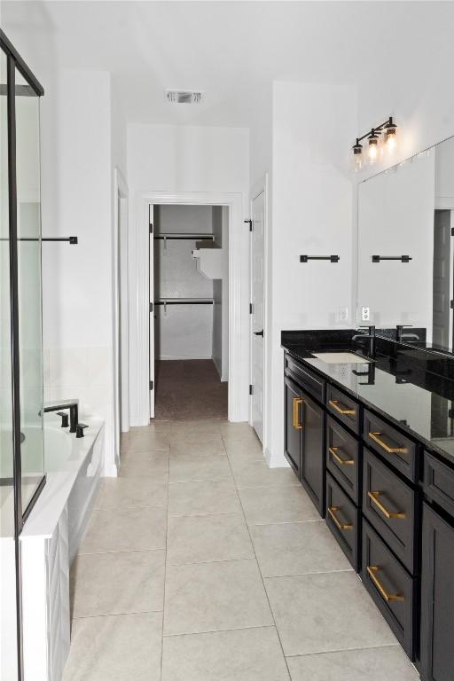 3437 Jaulan St, Leander, TX 78641 - bathroom featuring tile patterned floors, a garden tub, vanity, and a spacious closet