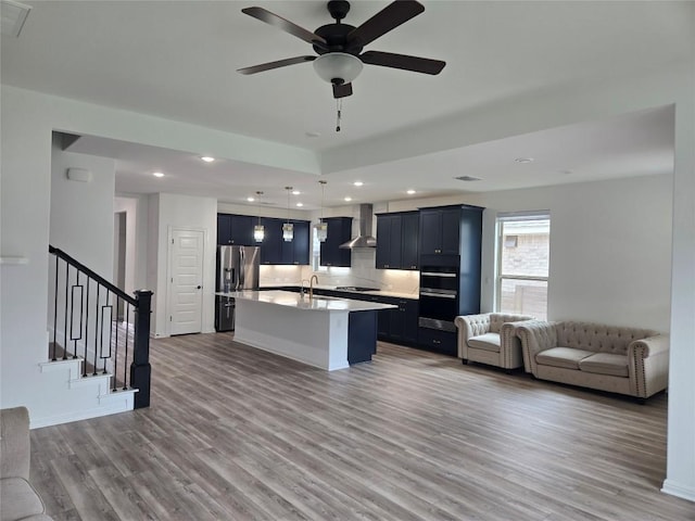 3437 Jaulan St, Leander, TX 78641 - kitchen with wall chimney range hood, open floor plan, stainless steel fridge with ice dispenser, light countertops, and wood finished floors