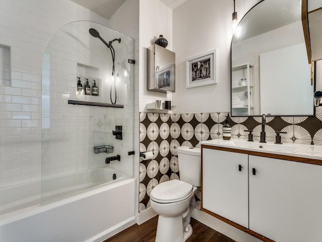 bathroom with toilet, wood finished floors, bathing tub / shower combination, vanity, and tile walls