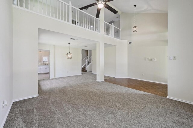 1605 Woods Blvd, Round Rock, TX 78681 - unfurnished living room featuring carpet floors, stairs, ceiling fan, a towering ceiling, and a chandelier