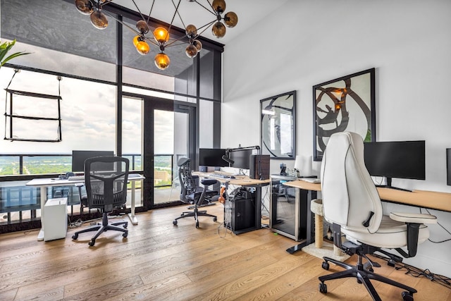 home office featuring a high ceiling, wood finished floors, and a chandelier