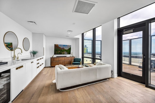 living room with wine cooler, floor to ceiling windows, and light wood-style floors