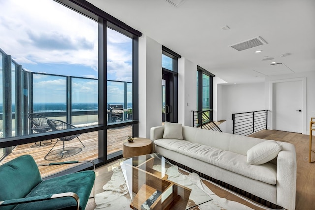 living area featuring a wall of windows, wood finished floors, and a water view