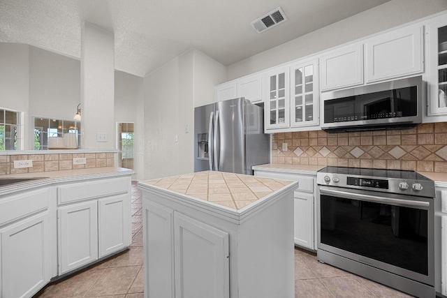 498 Aspen Cir, Killeen, TX 76549 - kitchen with stainless steel appliances, light tile patterned floors, decorative backsplash, and white cabinets