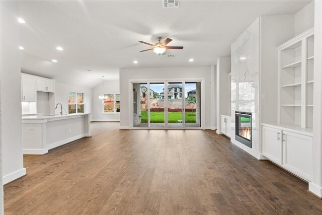 422 Sitlington Ln, Austin, TX 78738 - unfurnished living room featuring a premium fireplace, a ceiling fan, healthy amount of natural light, wood finished floors, and recessed lighting
