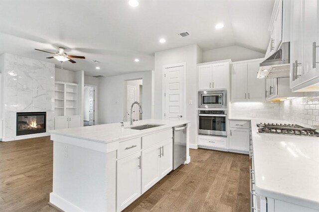 422 Sitlington Ln, Austin, TX 78738 - kitchen featuring a sink, stainless steel appliances, light wood-type flooring, ceiling fan, and a center island with sink