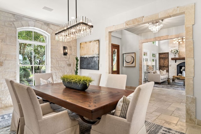 11949 Overlook Pass, Austin, TX 78738 - dining area featuring a chandelier, stone tile floors, and a large fireplace