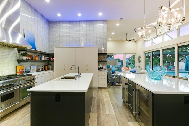 116 Wennmohs Pl, Horseshoe Bay, TX 78657 - kitchen with a center island with sink, beverage cooler, wall chimney range hood, double oven range, and a sink