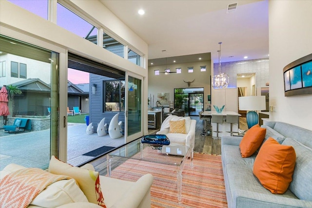living room with a chandelier, wood finished floors, recessed lighting, and a high ceiling