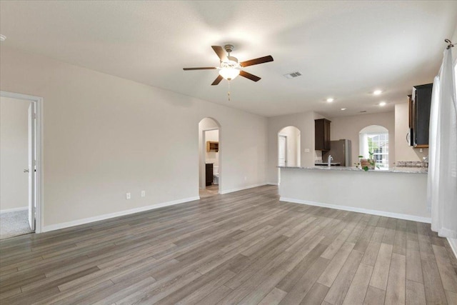 321 Freedom Park Ave, Liberty Hill, TX 78642 - unfurnished living room with arched walkways, ceiling fan, light wood-type flooring, recessed lighting, and baseboards