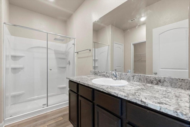 321 Freedom Park Ave, Liberty Hill, TX 78642 - full bath featuring a shower stall, wood finished floors, vanity, a textured wall, and a walk in closet