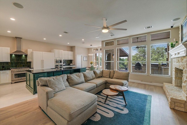 living room featuring a ceiling fan, healthy amount of natural light, light wood-type flooring, recessed lighting, and baseboards