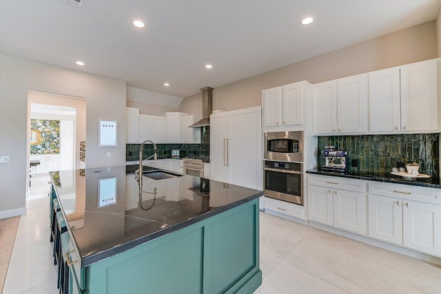 kitchen featuring stainless steel appliances, a sink, tasteful backsplash, recessed lighting, and wall chimney exhaust hood