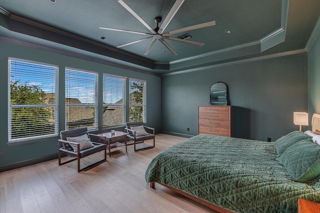 bedroom with a tray ceiling, ornamental molding, light wood-style flooring, baseboards, and a ceiling fan
