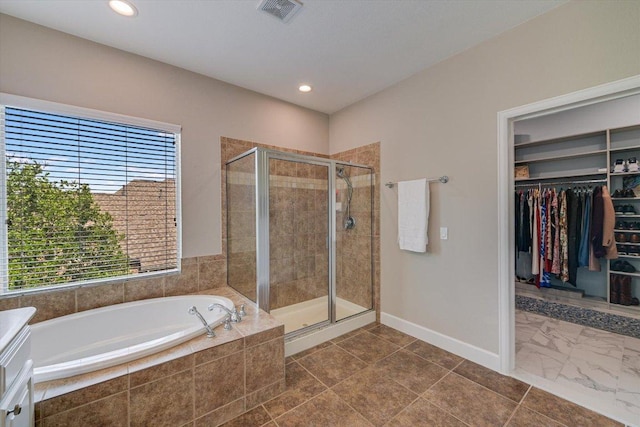 bathroom featuring a stall shower, a bath, baseboards, a walk in closet, and recessed lighting