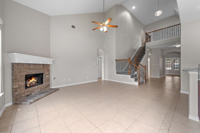 2640 Estefania Ln, Round Rock, TX 78665 - unfurnished living room with high vaulted ceiling, arched walkways, a ceiling fan, a fireplace, and stairs