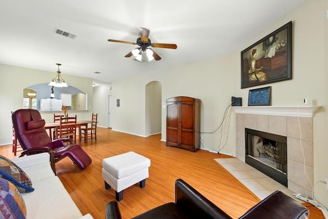 9403 Brandts Wood St, Austin, TX 78744 - living room with arched walkways, wood finished floors, a ceiling fan, and a tiled fireplace