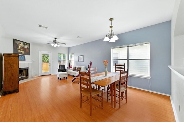 9403 Brandts Wood St, Austin, TX 78744 - dining room with light wood finished floors, a fireplace, ceiling fan, and a chandelier