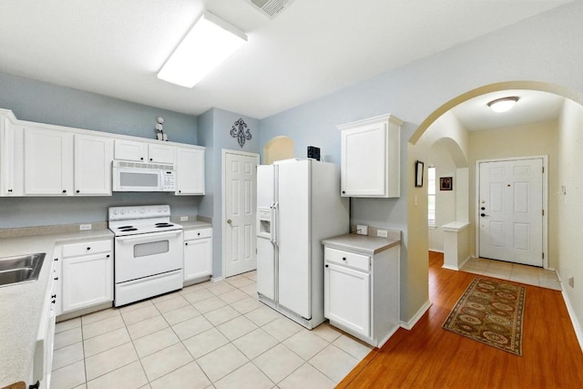 9403 Brandts Wood St, Austin, TX 78744 - kitchen with white appliances, arched walkways, light countertops, and white cabinets