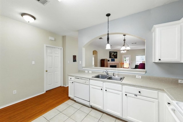 9403 Brandts Wood St, Austin, TX 78744 - kitchen with white dishwasher, arched walkways, hanging light fixtures, light wood finished floors, and light countertops