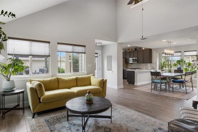 141 Witchhazel Way, San Marcos, TX 78666 - living room featuring plenty of natural light, light wood-type flooring, baseboards, high vaulted ceiling, and a chandelier