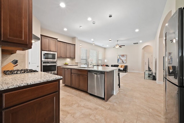 6321 Llano Stage Trl, Austin, TX 78738 - kitchen with stainless steel appliances, arched walkways, a ceiling fan, backsplash, and open floor plan
