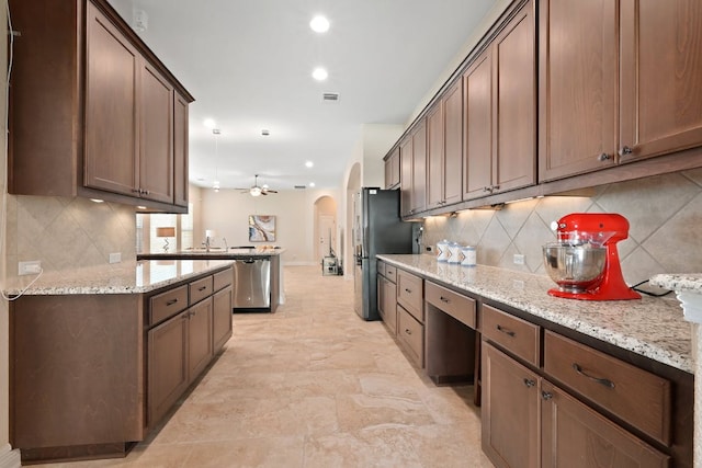 6321 Llano Stage Trl, Austin, TX 78738 - kitchen featuring arched walkways, tasteful backsplash, appliances with stainless steel finishes, recessed lighting, and light stone countertops
