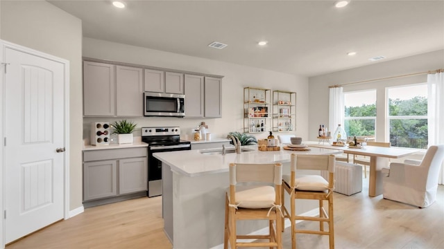 100 Heatherwood Ter, Marble Falls, TX 78654 - kitchen with gray cabinets, stainless steel appliances, a sink, light countertops, and a kitchen island with sink