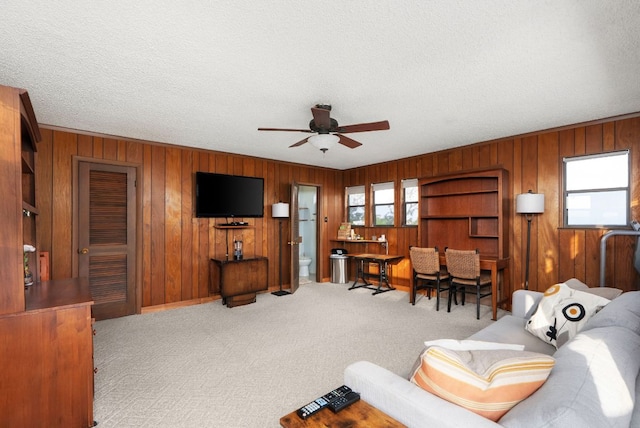 8016 Lupe Ln, Jonestown, TX 78645 - carpeted living room featuring wood walls, a ceiling fan, a textured ceiling, and crown molding