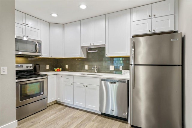 935 La Posada Dr Unit 158, Austin, TX 78752 - kitchen featuring appliances with stainless steel finishes, a sink, light countertops, light wood finished floors, and white cabinetry