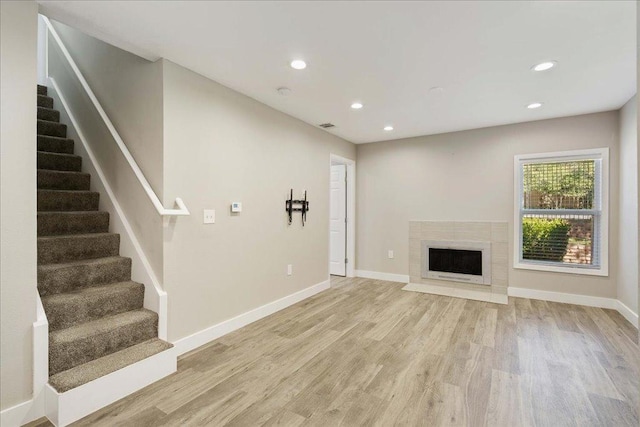 935 La Posada Dr Unit 158, Austin, TX 78752 - unfurnished living room with stairway, light wood-style floors, baseboards, recessed lighting, and a fireplace with flush hearth