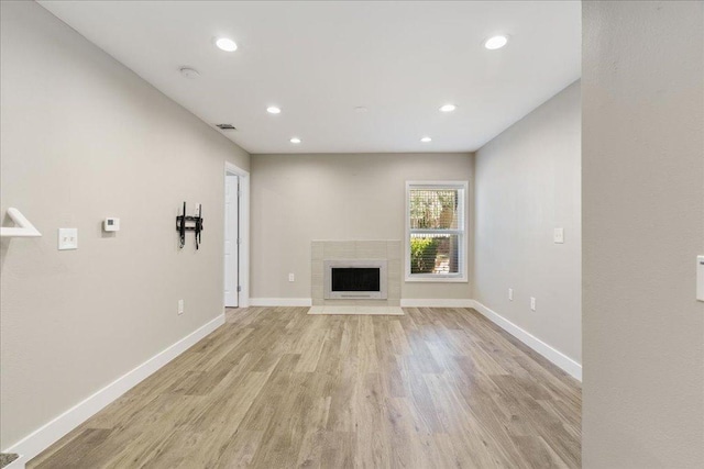 935 La Posada Dr Unit 158, Austin, TX 78752 - unfurnished living room with light wood-type flooring, baseboards, a tile fireplace, and recessed lighting