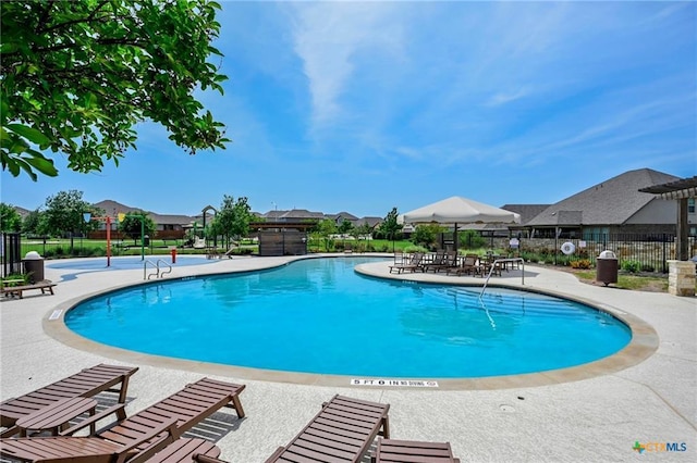 community pool featuring fence, a patio area, and a residential view