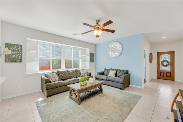 living area with plenty of natural light, light tile patterned floors, ceiling fan, and baseboards