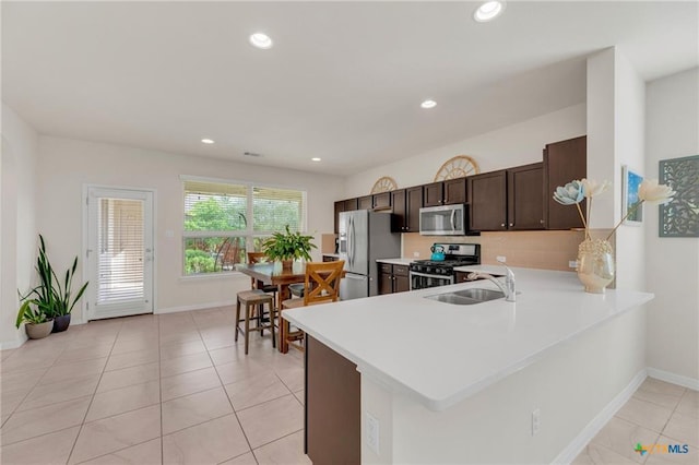 512 Canadian Springs Dr, Leander, TX 78641 - kitchen with stainless steel appliances, light countertops, dark brown cabinets, recessed lighting, and light tile patterned flooring