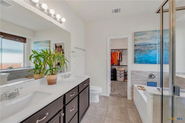 512 Canadian Springs Dr, Leander, TX 78641 - bathroom featuring double vanity, tile patterned flooring, a bath, a stall shower, and a walk in closet