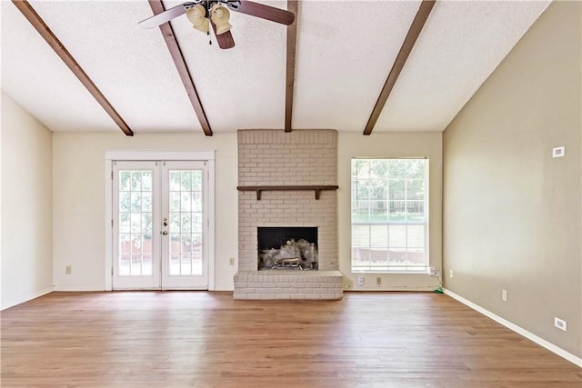 7309 Whispering Oaks Dr, Austin, TX 78745 - unfurnished living room featuring wood finished floors, a ceiling fan, french doors, a textured ceiling, and a brick fireplace