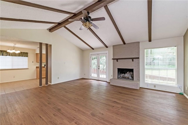 7309 Whispering Oaks Dr, Austin, TX 78745 - unfurnished living room featuring ceiling fan, a chandelier, wood finished floors, french doors, and a brick fireplace