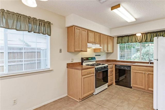 7309 Whispering Oaks Dr, Austin, TX 78745 - kitchen featuring dishwasher, gas range, under cabinet range hood, freestanding refrigerator, and a textured ceiling