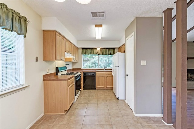 7309 Whispering Oaks Dr, Austin, TX 78745 - kitchen with gas stove, dishwasher, freestanding refrigerator, under cabinet range hood, and light tile patterned flooring